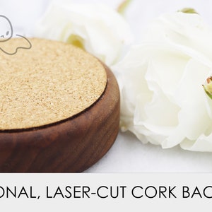 May include: A round, wooden coaster with a cork backing. The coaster is brown with a natural wood finish. The cork backing is a light brown colour.
