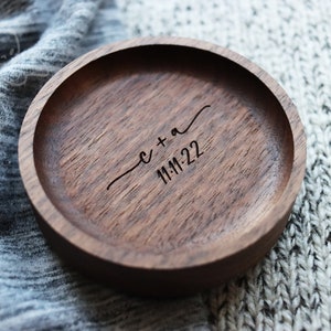 May include: A round wooden ring dish with a dark brown finish. The dish is engraved with the text "c + a 11-11-22".