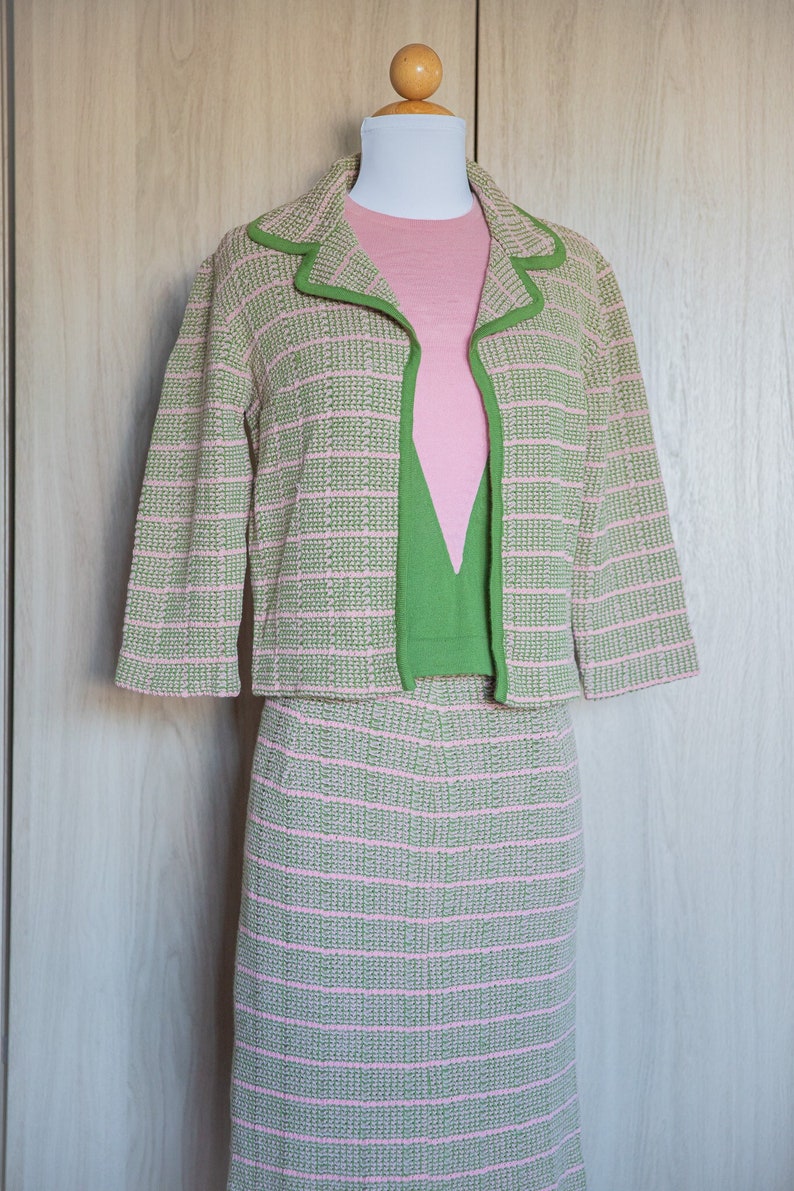 May include: A pink and green striped knit jacket and skirt set. The jacket has a green trim and the skirt is knee-length.