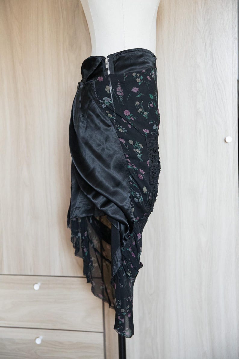 Peut inclure: Jupe noire avec un motif floral et un rev&ecirc;tement en satin. La jupe est dot&eacute;e d'une fermeture &eacute;clair et d'un design superpos&eacute; avec une bordure en dentelle. L'imprim&eacute; floral comprend des accents roses et verts.