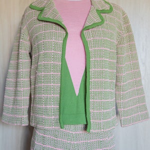 May include: A pink and green knit skirt suit with a matching top. The jacket has a green trim and the skirt and top have a pink and green checkered pattern.