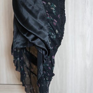 Peut inclure: Robe noire &agrave; imprim&eacute; floral avec un panneau en satin. La robe pr&eacute;sente un motif floral d&eacute;licat dans les tons de rose et de vert sur fond noir. La conception comprend une bordure en dentelle et une jupe fluide et superpos&eacute;e.