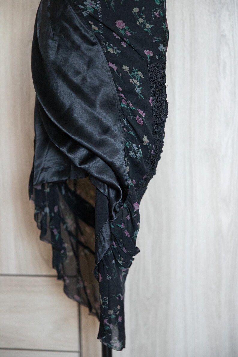 Peut inclure: Robe noire &agrave; imprim&eacute; floral avec un panneau en satin. La robe pr&eacute;sente un motif floral d&eacute;licat dans les tons de rose et de vert sur fond noir. La conception comprend une bordure en dentelle et une jupe fluide et superpos&eacute;e.