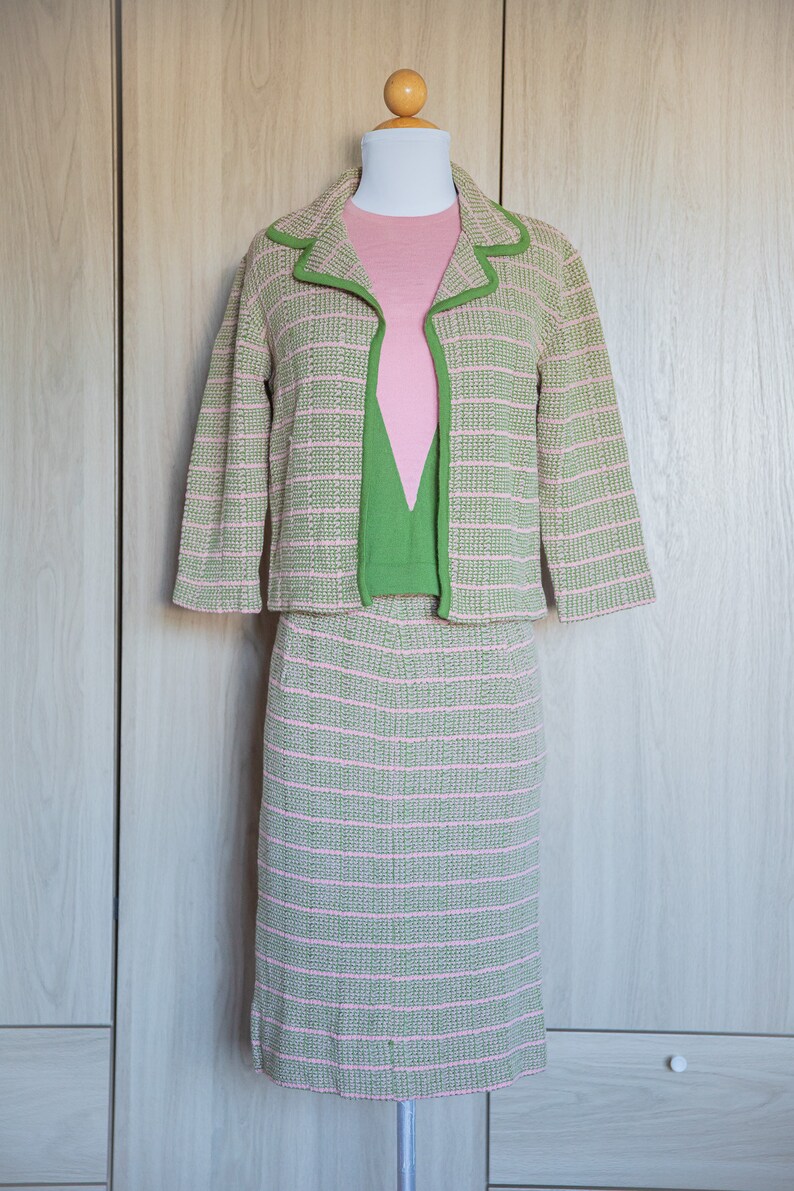 May include: A green and pink striped knit jacket and skirt set. The jacket has a green trim and the skirt is knee-length.