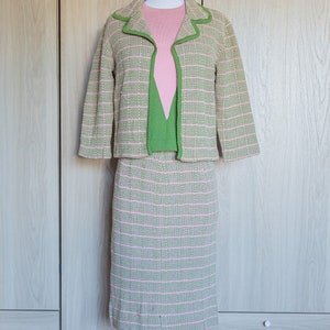 May include: A pink and green striped knit suit jacket and skirt set on a mannequin. The jacket has a green trim and the skirt is knee-length.