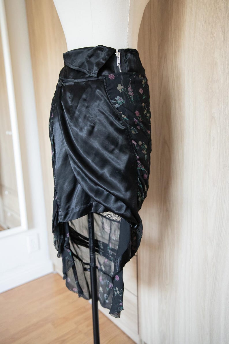 Peut inclure: Jupe en satin noir avec un design drap&eacute;. La jupe pr&eacute;sente un panneau &agrave; imprim&eacute; floral et une fermeture &eacute;clair. La jupe est pr&eacute;sent&eacute;e sur un mannequin.