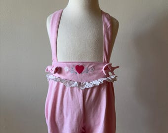 Puede incluir: Pantalón de peto rosa para bebé con ribete de encaje blanco y un corazón rojo bordado en la parte delantera.