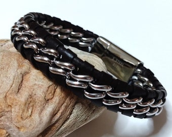 May include: A black leather bracelet with a silver chain interwoven. The bracelet has a magnetic clasp.