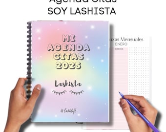May include: A rainbow-colored planner with the text "Mi Agenda Citas 2023" and "Lashista" with eyelashes. The planner has a black spiral binding and a pink and white page with the text "Citas Mensuales Enero" and "Egresos".
