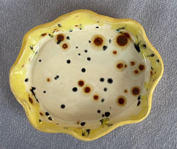 A hand-pinched ceramic plate with a wild leopard-print glaze — functional art that doubles as a conversation piece on any cheese board.