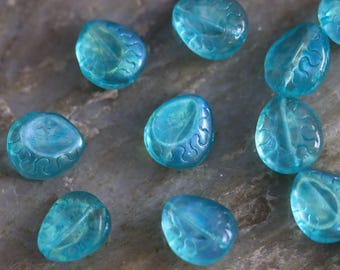 May include: A collection of ten turquoise blue glass beads with a wave-like pattern. The beads are smooth and translucent.