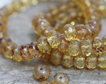May include: A strand of faceted amber glass beads. The beads are a light yellow color and have a slightly iridescent finish. The beads are strung on a clear thread.