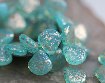 May include: Teal blue glass beads with gold flecks. The beads are teardrop shaped and have a speckled, iridescent finish.