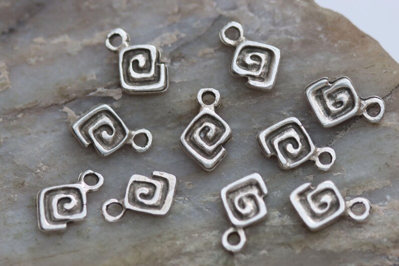Puede incluir: Diez abalorios de plata con forma cuadrada y dise&ntilde;o en espiral. Los abalorios tienen un agujero en la parte superior para sujetarlos a un collar o pulsera.