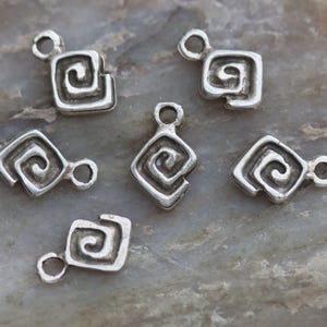Puede incluir: Seis colgantes de plata con forma cuadrada y dise&ntilde;o en espiral. Los colgantes tienen un agujero en la parte superior para sujetarlos a un collar o pulsera.