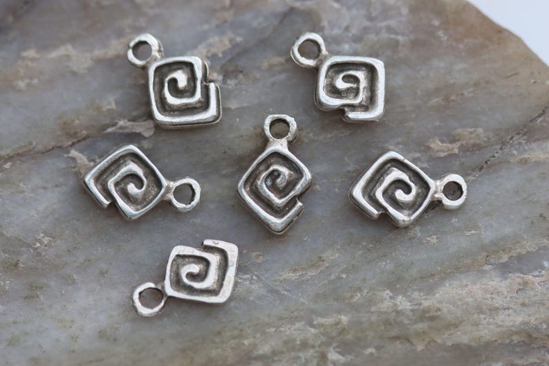 Puede incluir: Seis colgantes de plata con forma cuadrada y dise&ntilde;o en espiral. Los colgantes tienen un agujero en la parte superior para sujetarlos a un collar o pulsera.