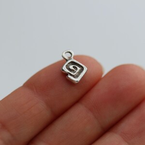 Puede incluir: Encanto de plata con un dise&ntilde;o en espiral en forma de diamante.