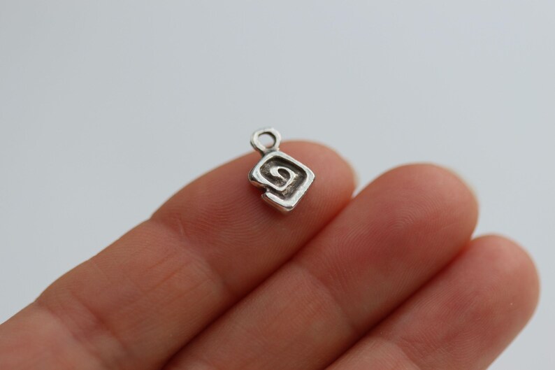 Puede incluir: Encanto de plata con un dise&ntilde;o en espiral en forma de diamante.