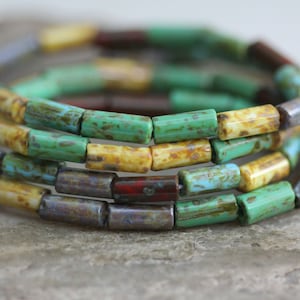May include: A close-up of a multi-coloured glass bead bracelet. The beads are a mix of turquoise, yellow, brown, and grey. The bracelet is made of multiple strands of beads.