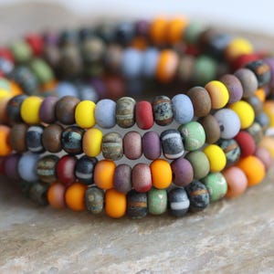 May include: A multi-coloured beaded bracelet with a variety of colours, including yellow, orange, red, brown, green, blue, and purple.