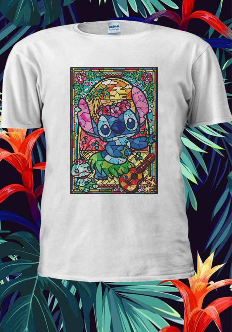 Pu&ograve; includere: Una maglietta bianca con un'immagine di Stitch di Lilo & Stitch che suona l'ukulele in stile vetrata. Stitch indossa una collana di fiori ed &egrave; circondato da piante tropicali e un tramonto.