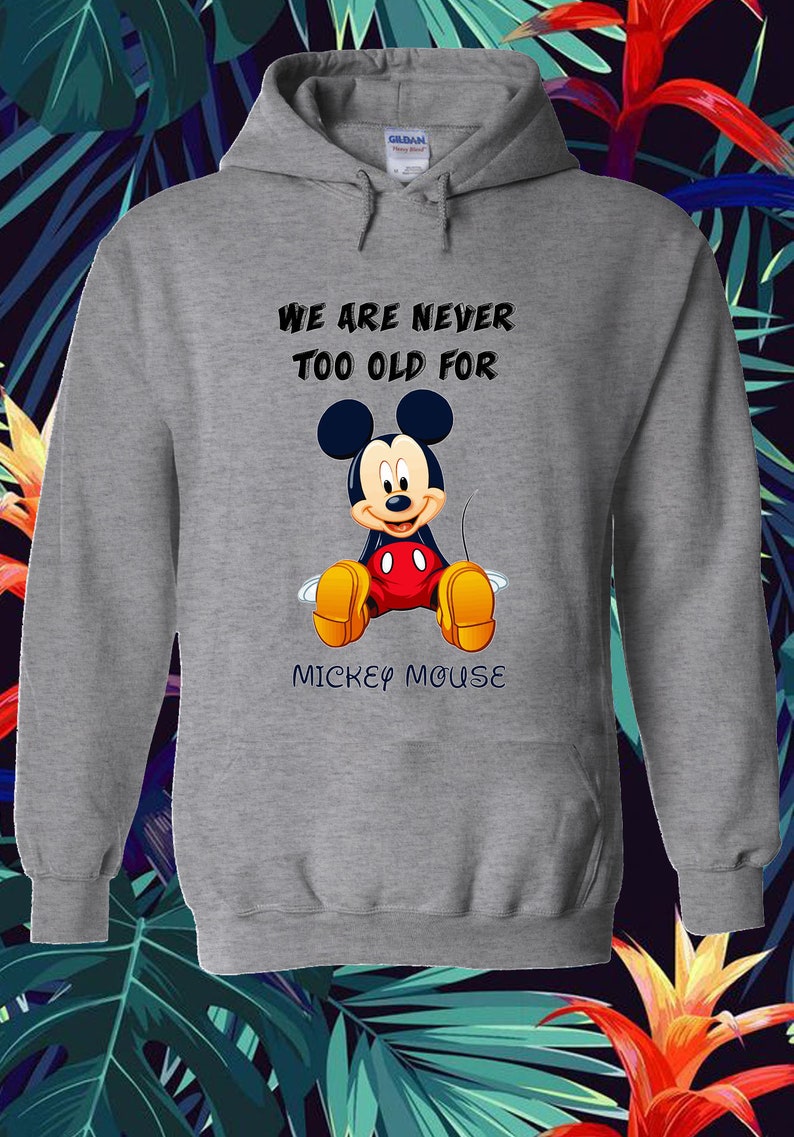 May include: A gray hooded sweatshirt featuring a graphic of Mickey Mouse. The text "WE ARE NEVER TOO OLD FOR MICKEY MOUSE" is printed above and below the character. The design includes Mickey's iconic ears, red shorts, and yellow shoes.