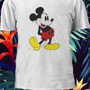 May include: White t-shirt with a cartoon image of Mickey Mouse in a red and black outfit. Mickey Mouse is smiling and walking with his arms at his sides.