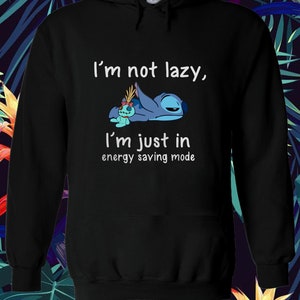 Puede incluir: Sudadera con capucha negra con un personaje azul Stitch de Lilo & Stitch. El texto en la sudadera dice "No soy perezoso, solo estoy en modo de ahorro de energ&iacute;a."