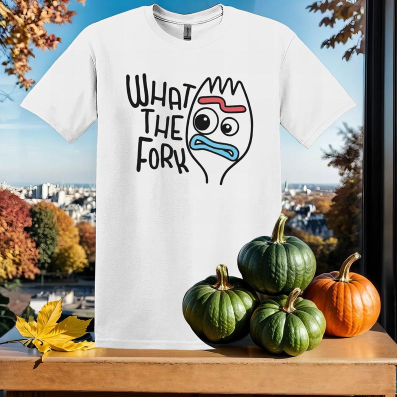 May include: White t-shirt with a cartoon character and the text "What the Fork" printed on it. The character is blue and red and has a surprised expression.