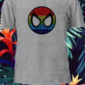 Puede incluir: Una camiseta gris con un logotipo de Spider-Man de colores arco&iacute;ris. El logotipo es un contorno negro de la m&aacute;scara de Spider-Man con un dise&ntilde;o de telara&ntilde;a de colores arco&iacute;ris.