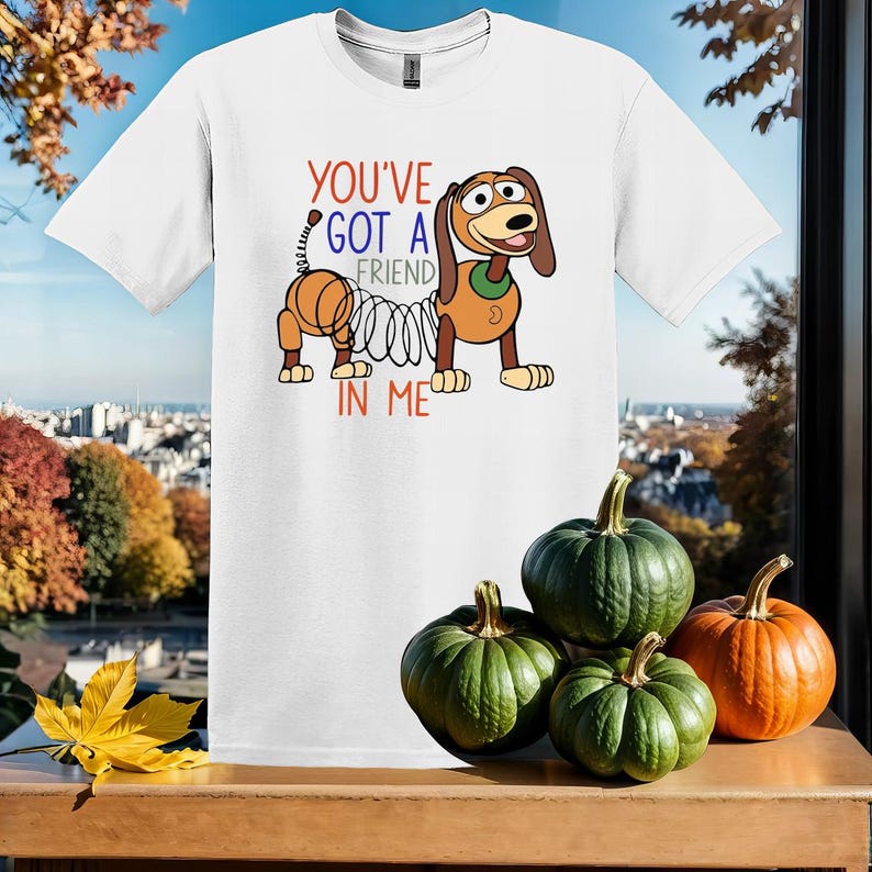 Puede incluir: Camiseta blanca con una imagen de dibujos animados de un perro con un resorte unido a su cola. El texto "You've got a friend in me" est&aacute; impreso en la camiseta.