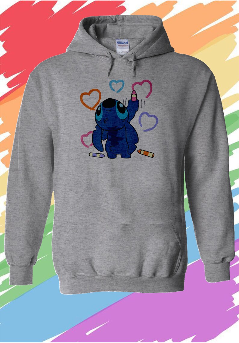 K&ouml;nnte beinhalten: Ein grauer Kapuzenpullover mit einer blauen Comicfigur, die Herzen mit bunten Buntstiften zeichnet. Die Figur hat gro&szlig;e blaue Augen und einen blauen K&ouml;rper. Der Hintergrund ist ein Regenbogen.