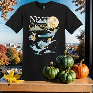 May include: Black t-shirt with the text "Never Grow Up" in white. The shirt features a cartoon image of Peter Pan and the Lost Boys flying in the air.