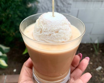 Peut inclure: Un bougeoir en verre avec une bougie blanche en forme de boule de crème fouettée. La bougie est surmontée d'une mèche.