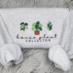 Puede incluir: Sudadera gris con plantas de interior bordadas y el texto "house plant collector".