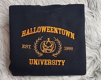 Può includere: Felpa nera con testo ricamato arancione che recita "Halloweentown University Est 1998" con una grafica di zucca.