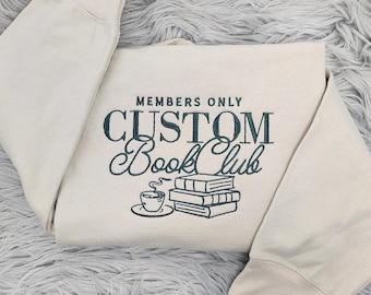 May include: A cream-colored sweatshirt with the text "MEMBERS ONLY CUSTOM BOOK CLUB" in dark blue lettering. A stack of books and a cup of coffee are illustrated below the text.