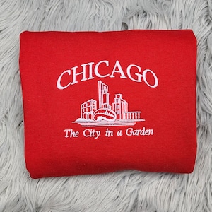 May include: Red sweatshirt with white embroidered text that reads "CHICAGO The City in a Garden".