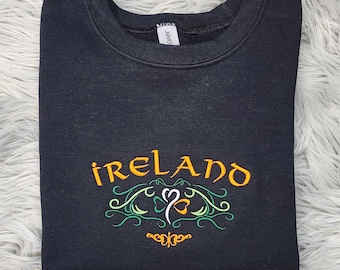 May include: Black sweatshirt with an embroidered design featuring the word "IRELAND" in orange lettering with green and white shamrock accents.