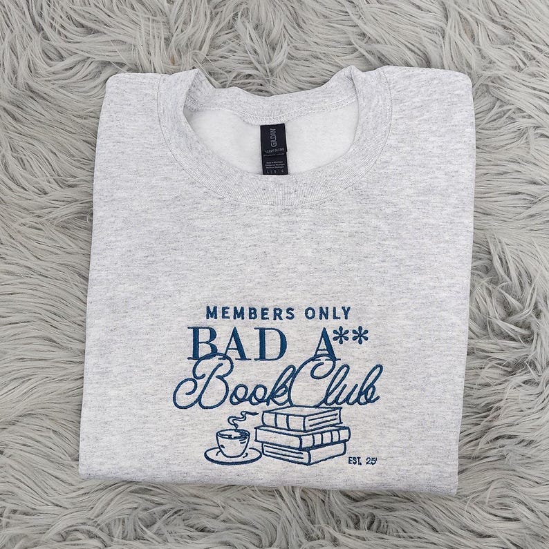 May include: Gray sweatshirt with the text "Members Only Bad A** Book Club Est. 29" in blue lettering. The text is stylized with a coffee cup and stack of books.