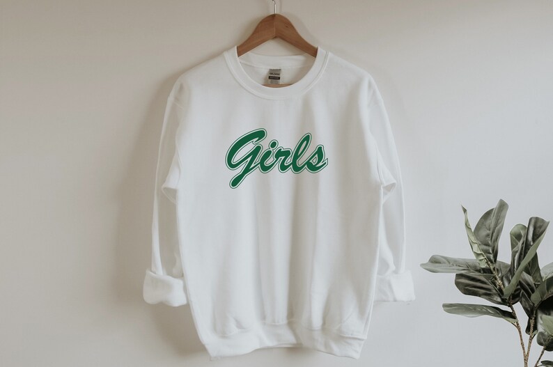 以下が含まれることがあります： 前面に緑色の「Girls」のグラフィックがプリントされた白いスウェットシャツ