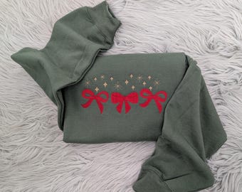 May include: A dark green sweatshirt with three red bows and gold glitter stars embroidered on the front.