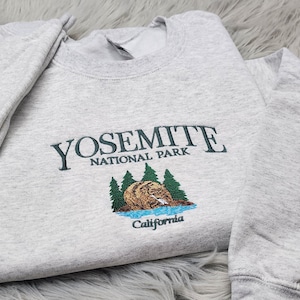May include: Gray sweatshirt with a green embroidered design that says "Yosemite National Park" with a bear and trees. The text "California" is below the design.