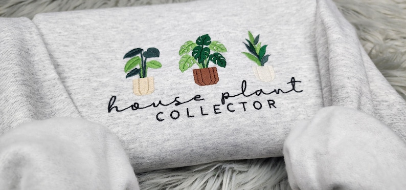 Puede incluir: Sudadera gris con plantas de interior bordadas y el texto "house plant collector".