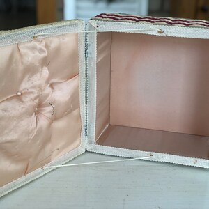 May include: A white and red striped fabric box with a white satin lining. The box is open and the lid is folded back.