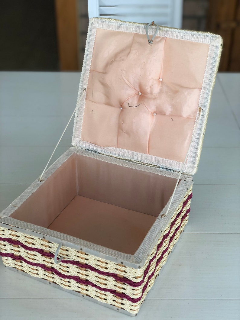 May include: A woven wicker box with a pink satin lining and a hinged lid. The box has a decorative trim of burgundy colored rope.