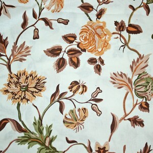 Peut inclure: Un tissu blanc avec un motif floral. Les fleurs sont brunes, orange et vertes. Le motif est un motif répétitif de fleurs et de feuilles.