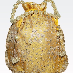 Peut inclure: Un sac à cordon de couleur or et blanc avec un motif floral. Le sac a une poignée perlée et un pompon.
