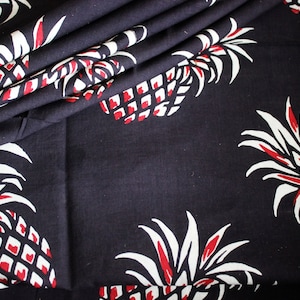 Può includere: Tessuto nero con stampa di ananas bianchi e rossi. Gli ananas sono stilizzati e hanno un design grafico.