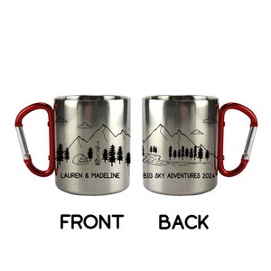 May include: A stainless steel travel mug with a red carabiner handle. The front of the mug features a mountain scene with a tent and campfire and the text "Lauren & Madeline". The back of the mug features a mountain scene with a river and the text "Big Sky Adventures 2024".